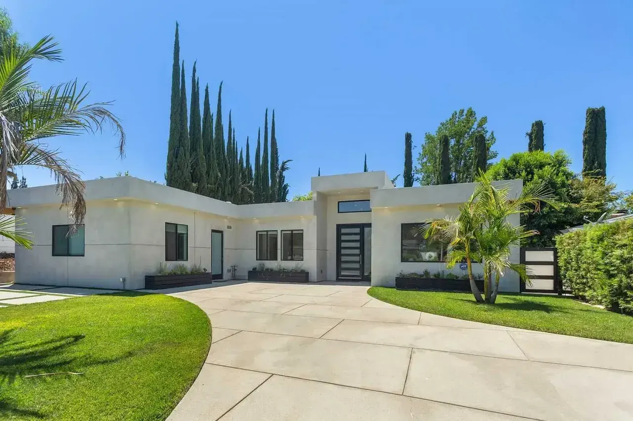 Modern stucco home with palm trees and cypress trees in Los Angeles