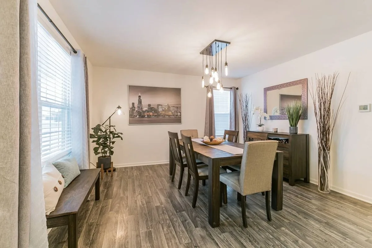 Bright dining room with a wood table, large windows and pendant lighting