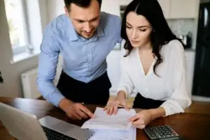 Couple reviewing how much does it cost to sell a house with closing documents and calculator