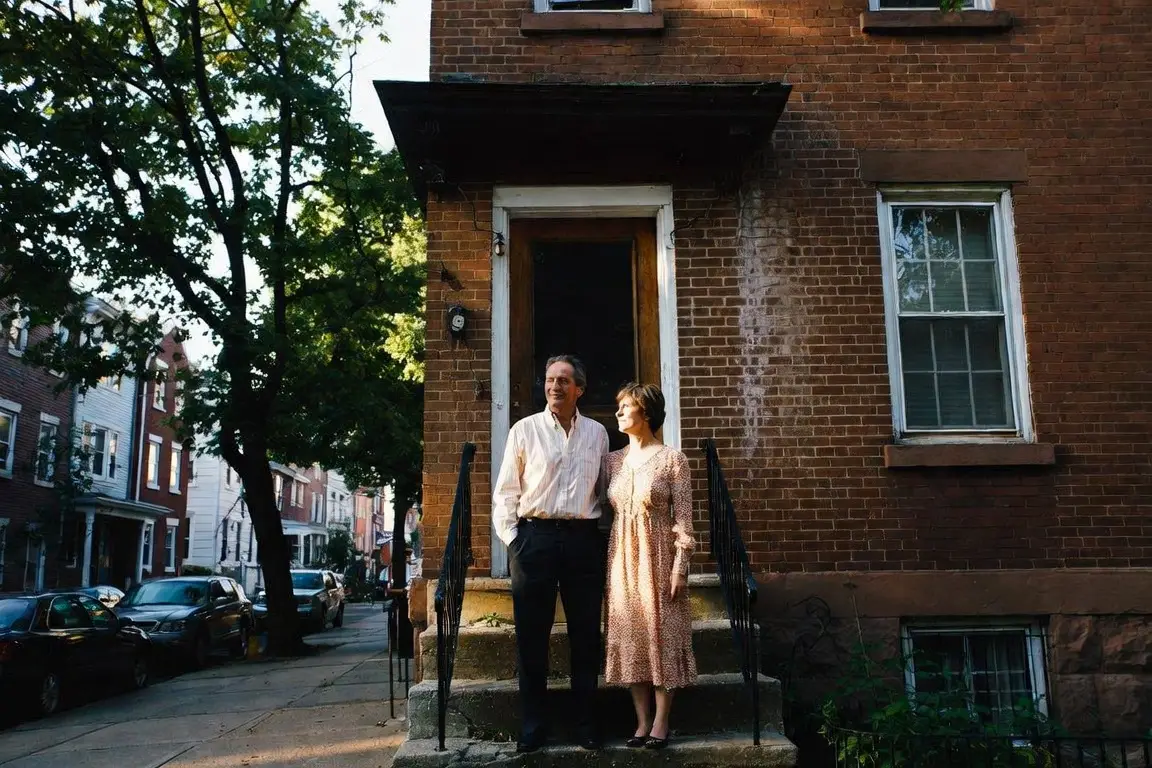 how to sell a house without a realtor in pennsylvania - couple standing on the front stoop of a Philadelphia brick rowhouse on a tree-lined street
