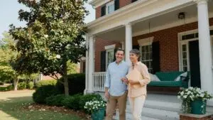 Who pays closing costs in Georgia: a couple on the porch of a brick home in metro Atlanta